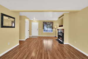Unfurnished living room featuring a fireplace with flush hearth and wood finished floors
