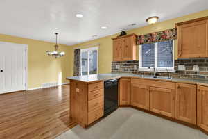 Kitchen featuring backsplash, a peninsula, black dishwasher, hanging light fixtures, and a textured ceiling