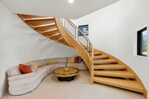 Curved hardwood staircase featuring a wood-finish handrail and metal balusters