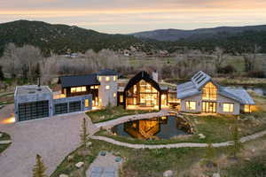 Contemporary architectural residence featuring multiple structures, a prominent pond, and a gravel driveway