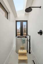 Contemporary bathroom featuring a cylindrical soaking tub, a matte black rain shower head, and a large skylight
