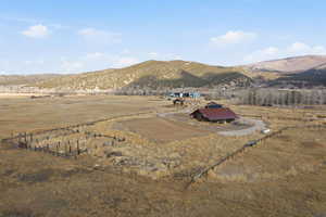 Expansive property featuring a large barn with a red metal roof, a curved gravel driveway, and extensive perimeter fencing