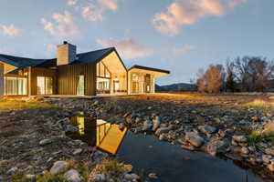 Modern architectural design featuring a prominent stone chimney and a dark-pitched roof