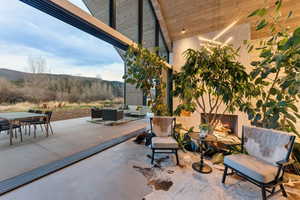 Expansive indoor-outdoor living space featuring a large sliding glass wall system, concrete flooring, a built-in fireplace, and a wood-paneled ceiling