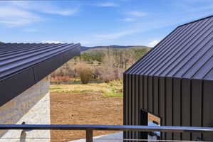 Modern architectural design featuring dark standing seam metal roofs and siding, a stone exterior, and a cable railing system