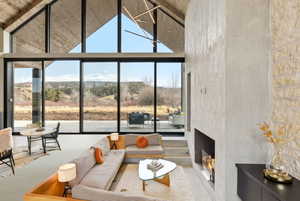 Expansive living area featuring a vaulted ceiling with wood-finish paneling, a contemporary linear fireplace, and floor-to-ceiling windows