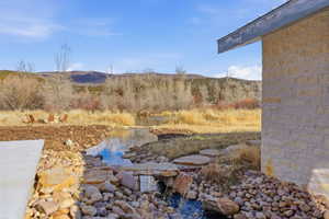 Natural waterway featuring river rock landscaping and a stone footbridge