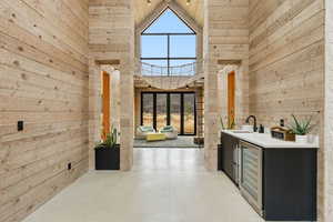 Bar area with wooden walls, finished concrete floors, a high ceiling, wine cooler, and light countertops