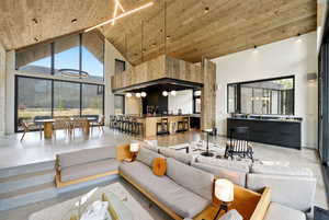 Sunken living room featuring concrete flooring and a high wooden ceiling
