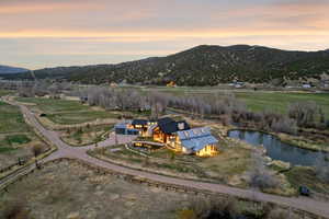 Expansive property featuring a contemporary residence with multiple structures, a private pond, and a large gravel driveway