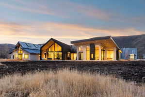 Modern architectural design featuring multiple structures, extensive glazing, and a backdrop of rolling hills