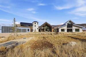 Contemporary architectural design featuring expansive glass panels, a stone-clad turret, and multiple garage bays with modern doors