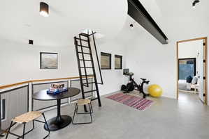 Loft space featuring high vaulted ceilings, industrial-style exposed beam, and polished concrete flooring