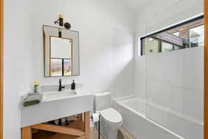 Bathroom featuring a white integrated sink vanity with a wood-finish base, a rectangular mirror with a black frame, and a matte black wall-mounted faucet
