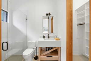 Modern bathroom featuring a glass-enclosed shower, freestanding toilet, and a vanity with an integrated sink