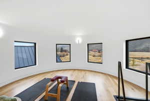 Curved white walls with multiple windows, light wood-finish flooring, and wall-mounted lighting fixtures