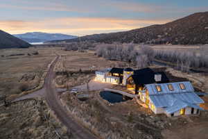 Expansive property featuring multiple structures, a private pond with a footbridge, and a gravel drive