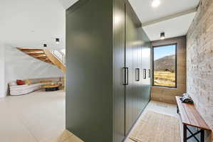 Entryway featuring a floor-to-ceiling storage wall with modern pulls, a large picture window, and a textured accent wall