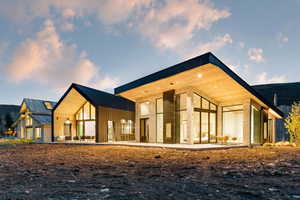 Modern architectural design featuring expansive glass panels, a stone and vertical siding exterior, and a distinctive black metal roofline