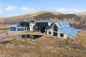 Modern architectural home featuring a prominent pitched metal roof, expansive glass doors, and solar panels