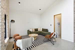 Living area featuring a vaulted ceiling and a stone accent wall with a fireplace opening