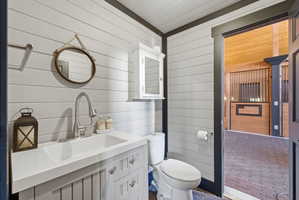 Powder room featuring horizontal plank wall paneling, a white vanity with integrated sink, and a two-piece toilet