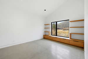 Unfurnished room with finished concrete flooring, vaulted ceiling, and a mountain view