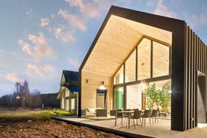 Contemporary gabled-roof architecture featuring extensive glass panels, light wood-finish siding, and a dark metal accent wall