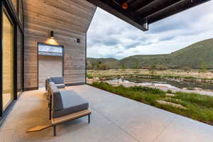 Expansive covered patio featuring a concrete surface, a wood-paneled exterior wall, and an integrated outdoor light fixture