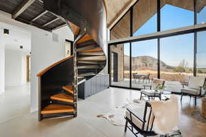 Living area with a mountain view, expansive windows, a high wood beamed ceiling, and concrete floors