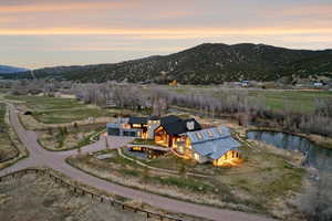 Expansive property featuring a modern architectural residence with multiple outbuildings, a private pond, and a winding gravel driveway