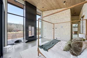 Full height windows, contemporary fireplace, and stone accent walls create a modern aesthetic