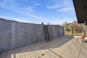 Expansive outdoor terrace featuring large format paver tiles and a dark metal railing system