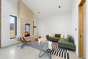 Vaulted living area featuring a stone fireplace, concrete flooring, and recessed lighting