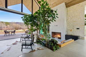 Spacious interior featuring a large fireplace with a concrete surround, wood-paneled vaulted ceiling, and polished concrete flooring