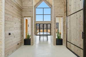 Vaulted entry hall featuring wood-finish paneling and polished concrete flooring