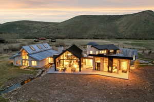 Contemporary architecture featuring a combination of stone and metal siding, expansive floor-to-ceiling windows, and multiple outdoor patio areas