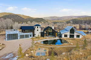 Rear view of house featuring driveway, a chimney, a mountain view, an outdoor pool, and a metal roof