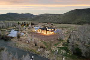 Modern architectural residence with expansive glass facades, a detached barn-style structure, and a large private pond