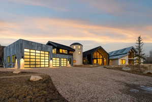Contemporary architectural design featuring multiple gables, a silo-inspired structure, and a three-car garage with frosted glass panel doors