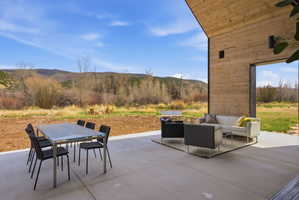 Expansive concrete patio with wood-paneled overhang, offering outdoor dining and lounge areas