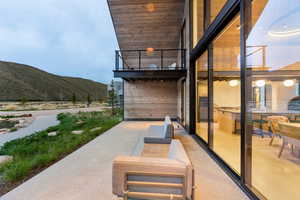 Expansive concrete patio with direct access to a second-story balcony featuring a black metal railing