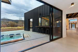 Expansive concrete patio featuring an integrated spa, a bar counter with seating, and a mountain backdrop