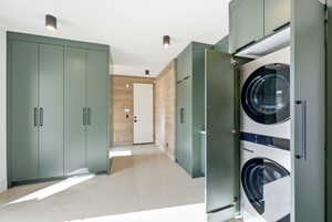 Integrated laundry area featuring stacked appliances within custom cabinetry