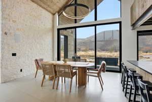 Spacious room featuring a stone accent wall, vaulted wood-finish ceiling, and expansive floor-to-ceiling windows