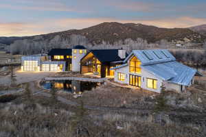 Rear view of property with driveway, stone siding, a mountain view, a chimney, and a standing seam roof
