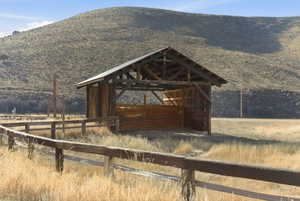 Open-sided wooden structure with a pitched roof, featuring exposed timber framing and wood plank siding