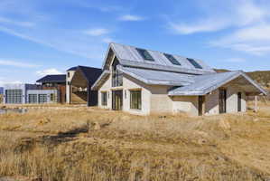 Contemporary architecture featuring a stone and metal exterior, multiple skylights, and expansive windows