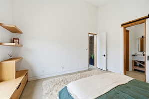 White walls with high ceilings, light wood-finish built-in shelving, and concrete-finish flooring