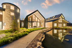 Unique architectural design featuring a stone-clad silo, large A-frame gables, and a tranquil pond